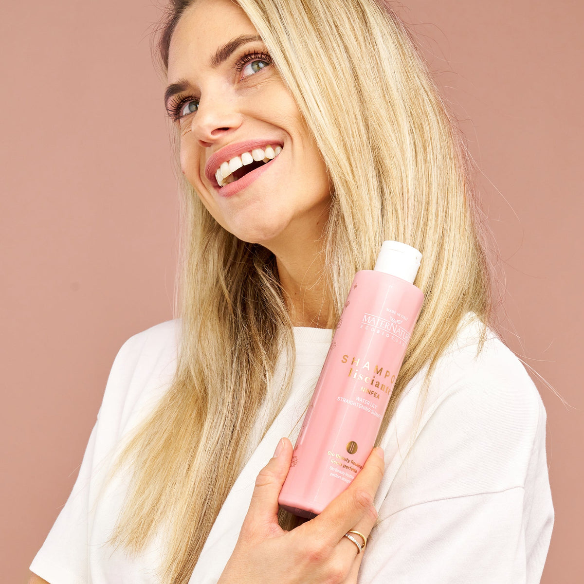 Modelo de pelo liso sosteniendo el champú de nenúfar Maternatura en su botella rosa
