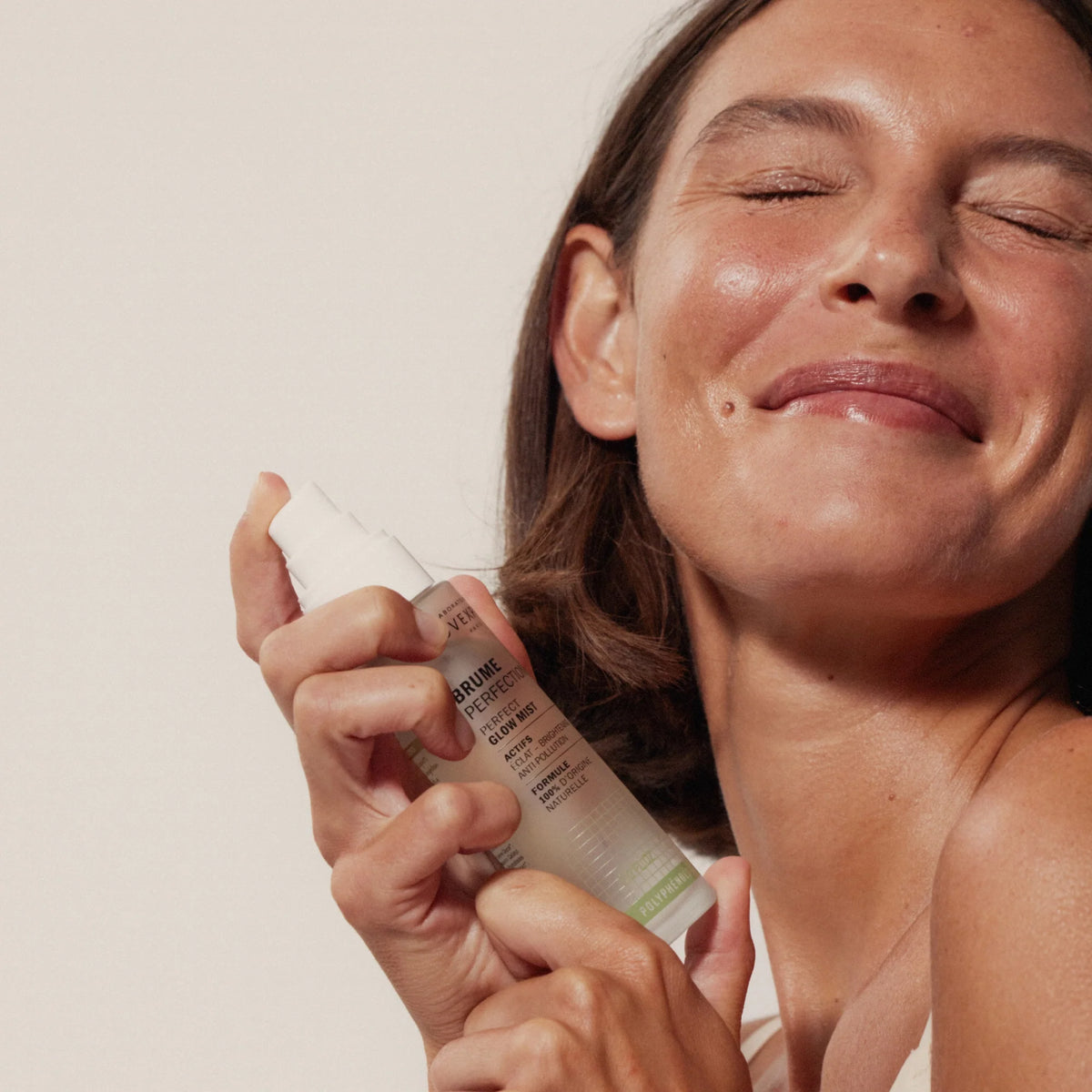 Modelo sosteniendo la Bruma Perfection Éclat de Novexpert junto al rostro con los ojos cerrados