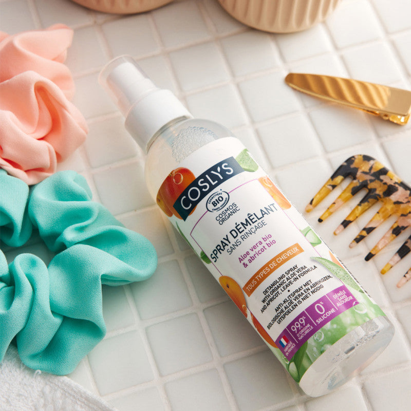 Spray desenredante Coslys con aloe vera y albaricoque junto a coleteros y un peine