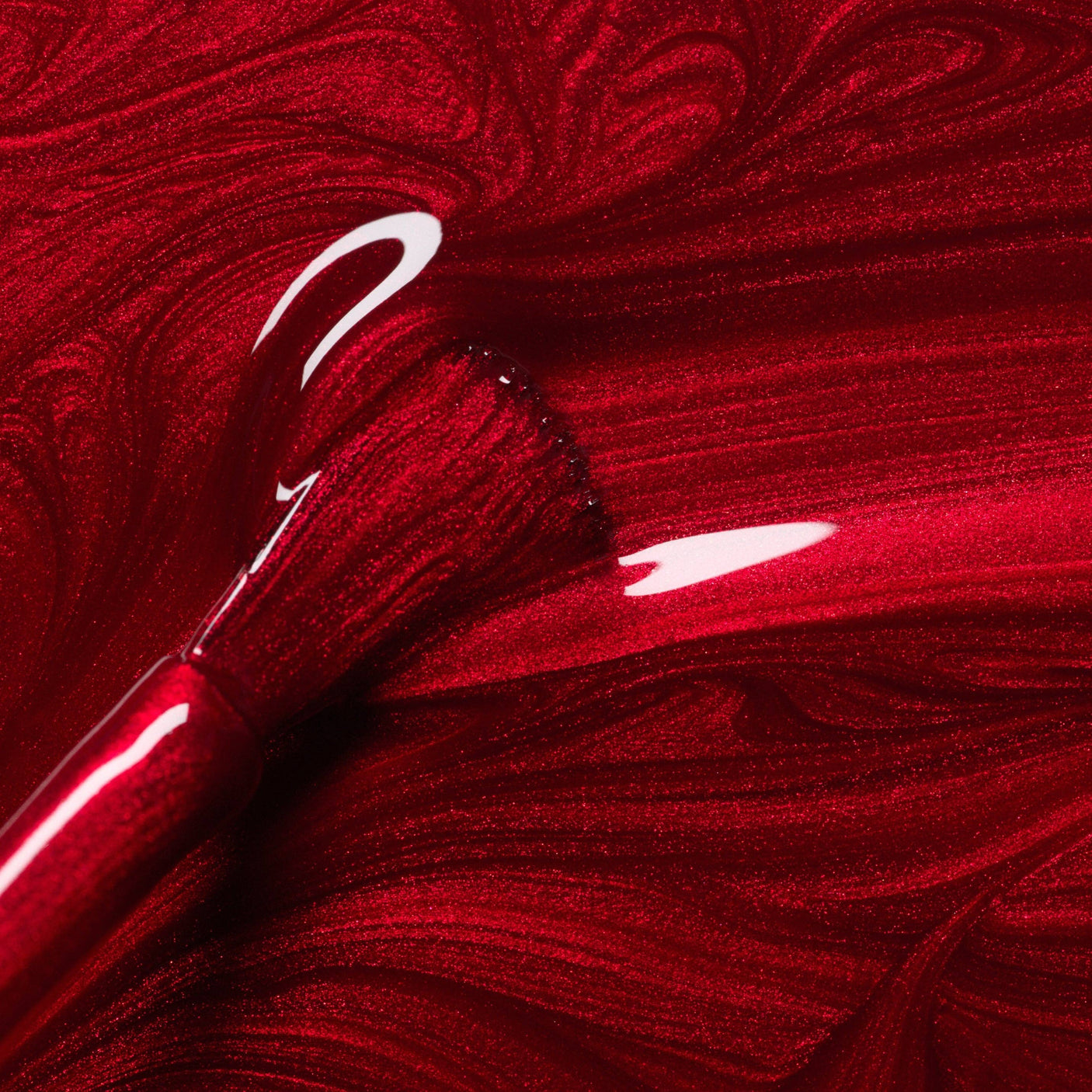 Primer plano del pincel con esmalte Red Hibiscus de Manucurist, mostrando su textura fluida y brillo intenso.