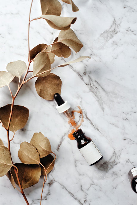 Sérum de cosmética orgánica junto a una rama de eucalipto, para una rutina facial que calma la piel con acné sin resecarla — Biovardi