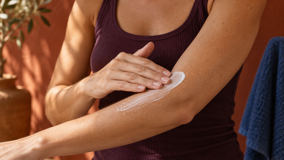 Manos extendiendo crema sobre un antebrazo después de la ducha; ilustración editorial creada con IA.