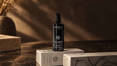 Aceite corporal Reverent Antioxidant Dry Body Oil de Twelve Beauty sobre sus cajas; ilustración editorial creada con IA.