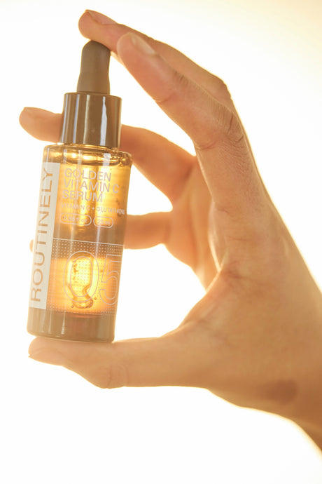 Frasco de sérum Routinely 05 Golden Vitamin C de 25 ml sostenido en una mano