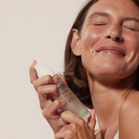 Modelo sosteniendo la Bruma Perfection Éclat de Novexpert junto al rostro con los ojos cerrados