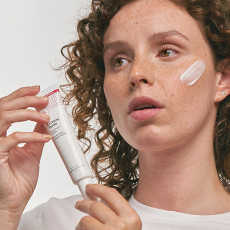 Modelo con una muestra de Crème Repulp de Novexpert sobre la mejilla y el tubo en la mano