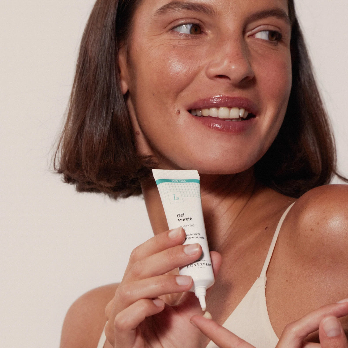 Modelo dispensando una pequeña cantidad de Novexpert Gel Pureté desde el tubo sobre un dedo