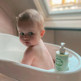 Gel de baño Happy Earth Baby & Kids de 300 ml junto a una bañera infantil