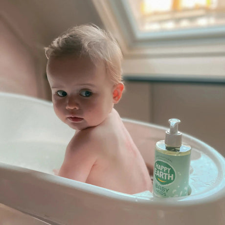 Gel de baño Happy Earth Baby & Kids de 300 ml junto a una bañera infantil