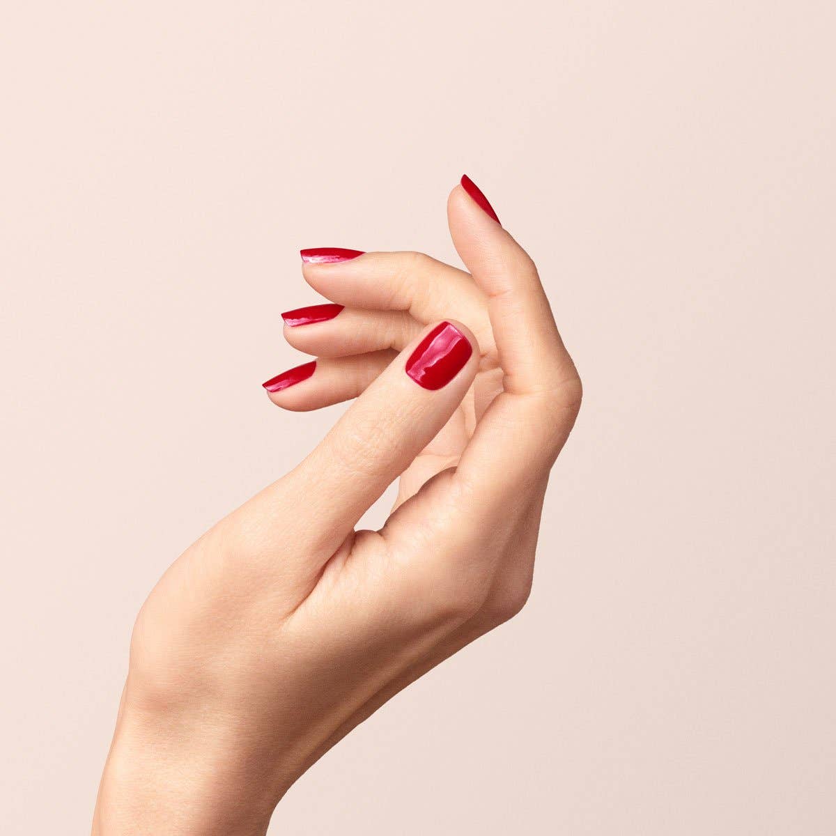 Manicura impecable en color rojo Granada con las manos naturales.
