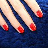 Contraste vibrante del esmalte rojo Anémone de Manucurist sobre un fondo azul profundo.