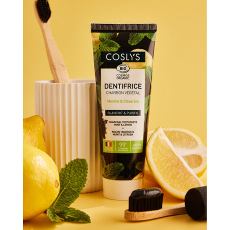 Tubo de dentífrico de carbón vegetal Coslys junto a limón, menta y cepillos de dientes
