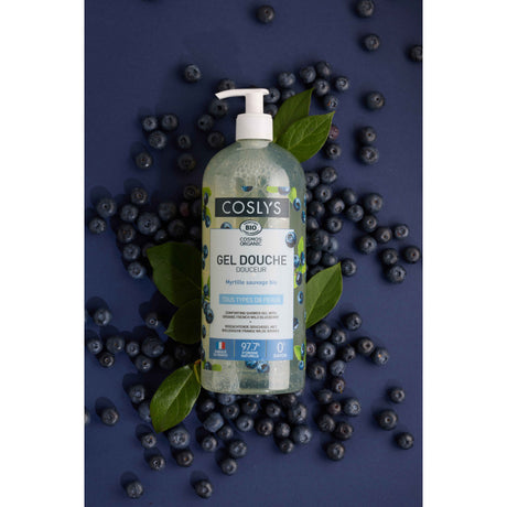Botella con dosificador del gel de ducha Coslys Arándano Silvestre sobre fondo azul con arándanos