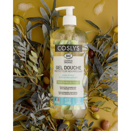 Botella con dosificador del gel de ducha de oliva Coslys entre ramas y aceitunas