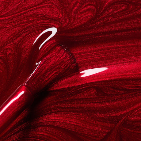 Primer plano del pincel con esmalte Red Hibiscus de Manucurist, mostrando su textura fluida y brillo intenso.