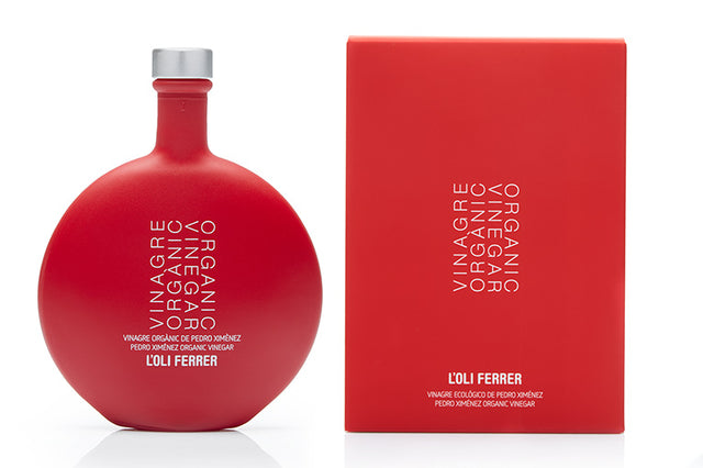 Vinagre ecológico Pedro Ximénez L’Oli Ferrer con botella y estuche rojo sobre fondo blanco